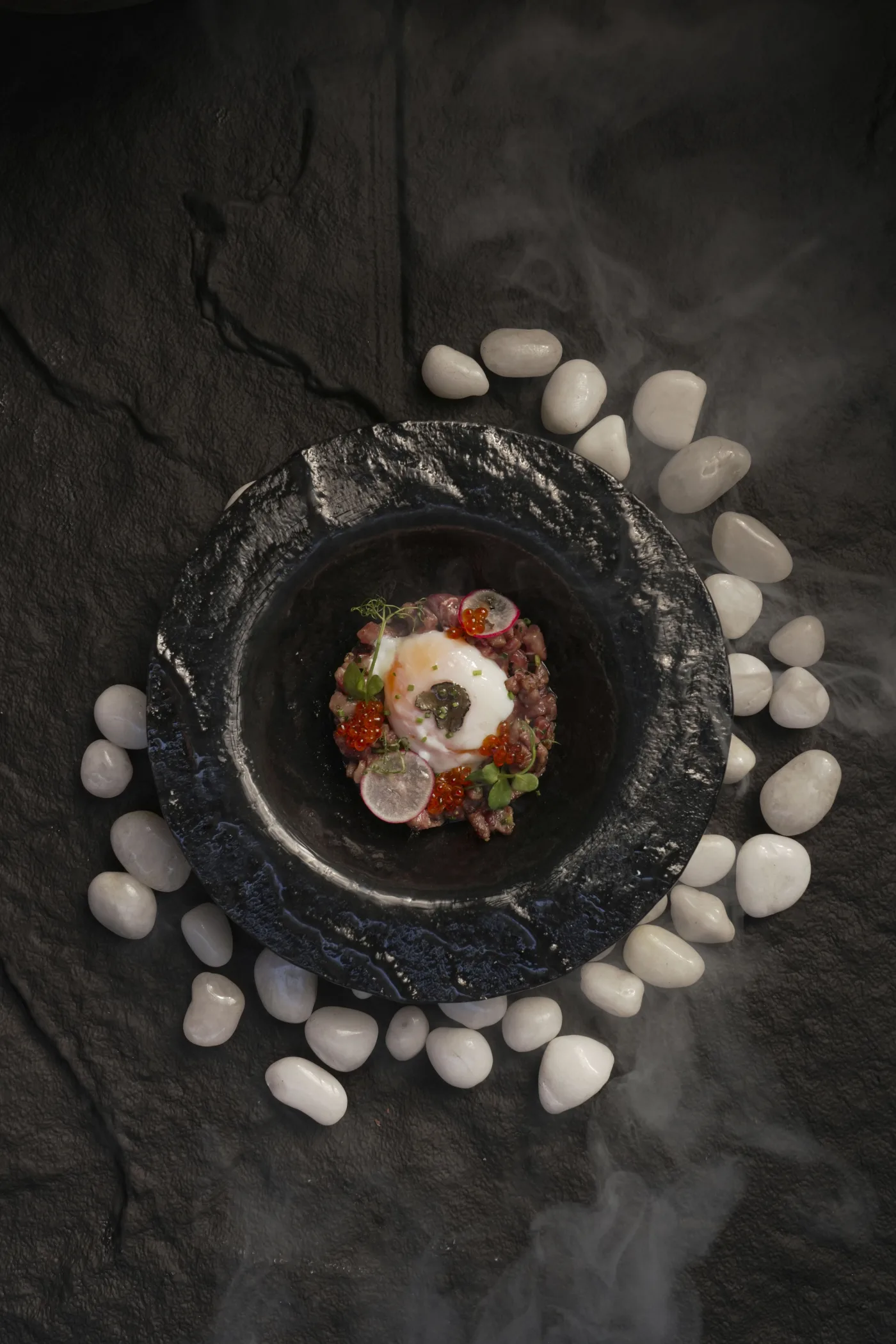 Tartar con huevo y huevas sobre cerámica oscura